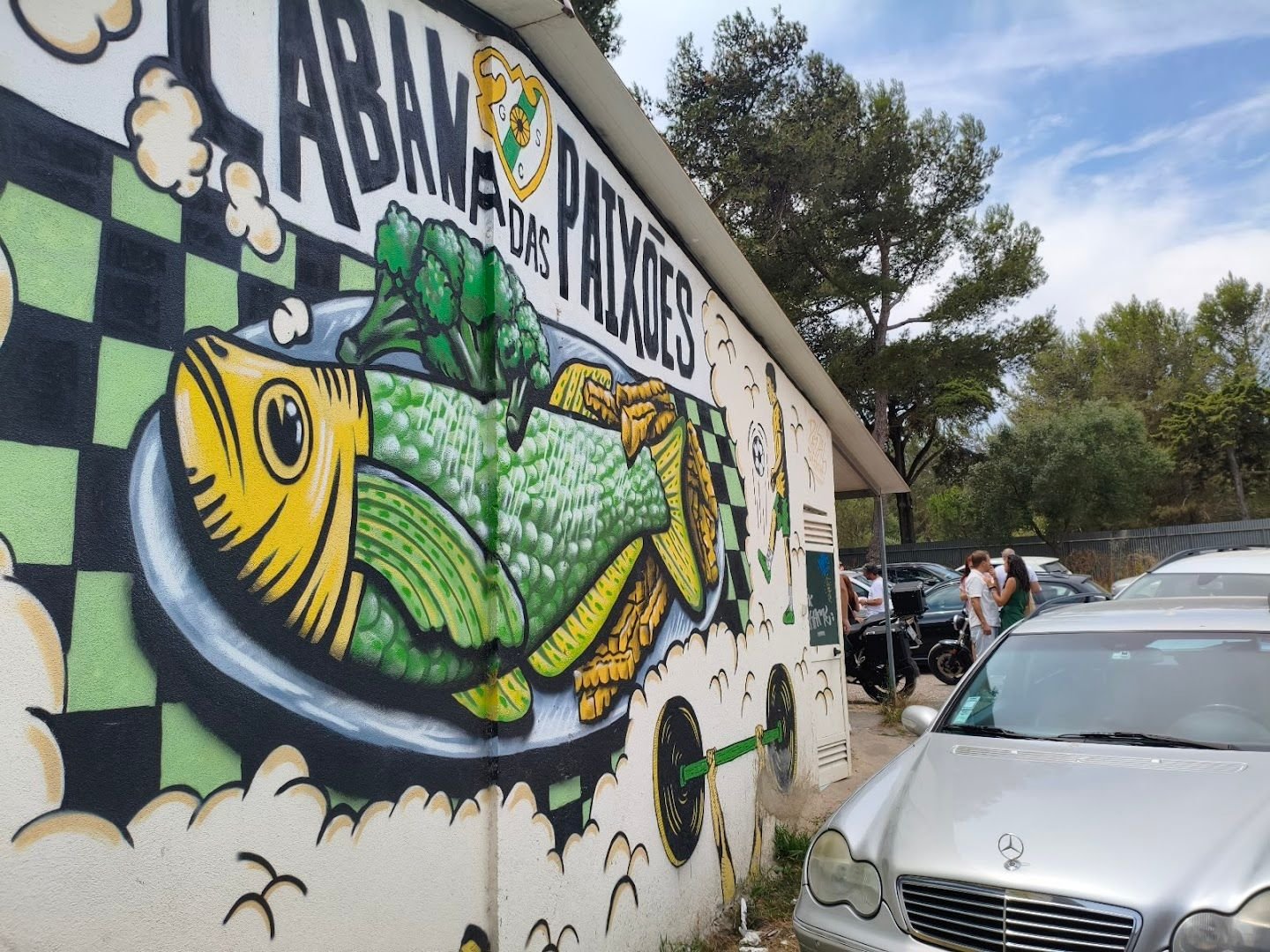 Mural pintado na parede da Cabana das Paixões: um peixe grelhado num prato, o emblema do clube e um futebolista